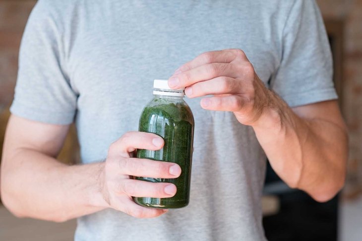 man holding bottle with green smoothie. detox drink and healthy lifestyle